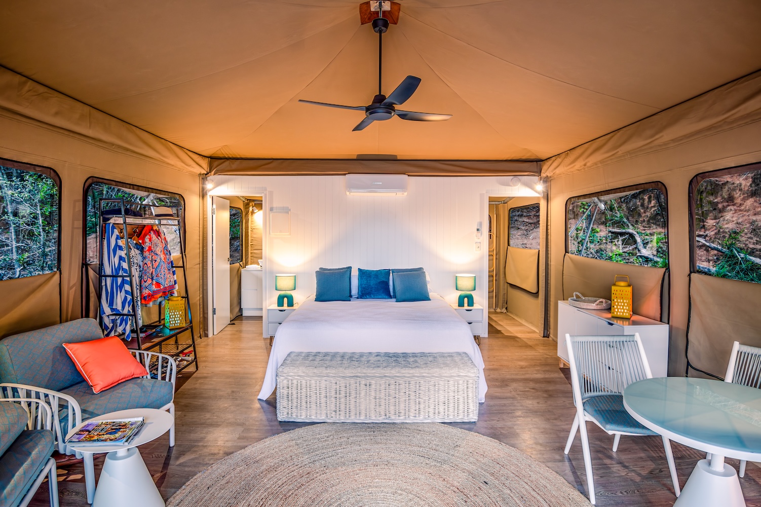 Inside a Magnetic Glamping safari tent — king bed, canvas walls, ceiling fan and a view into the tropical garden