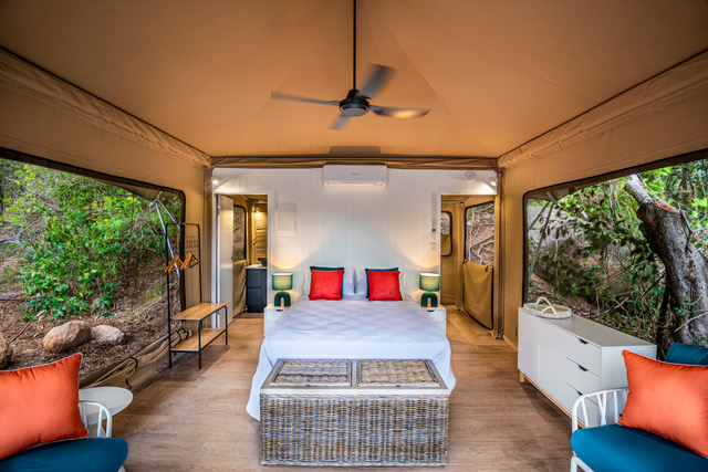 Tent 3 king bed dressed in white linen with orange accent cushions, Magnetic Glamping