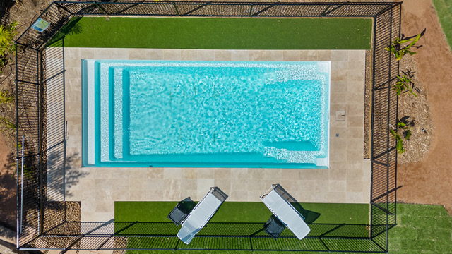 Fenced magnesium pool at Magnetic Glamping surrounded by lush tropical garden