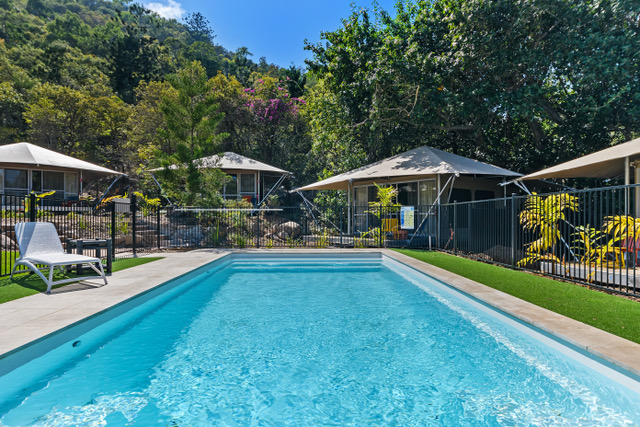Magnesium pool with tents framed by tropical mountain backdrop, Magnetic Glamping