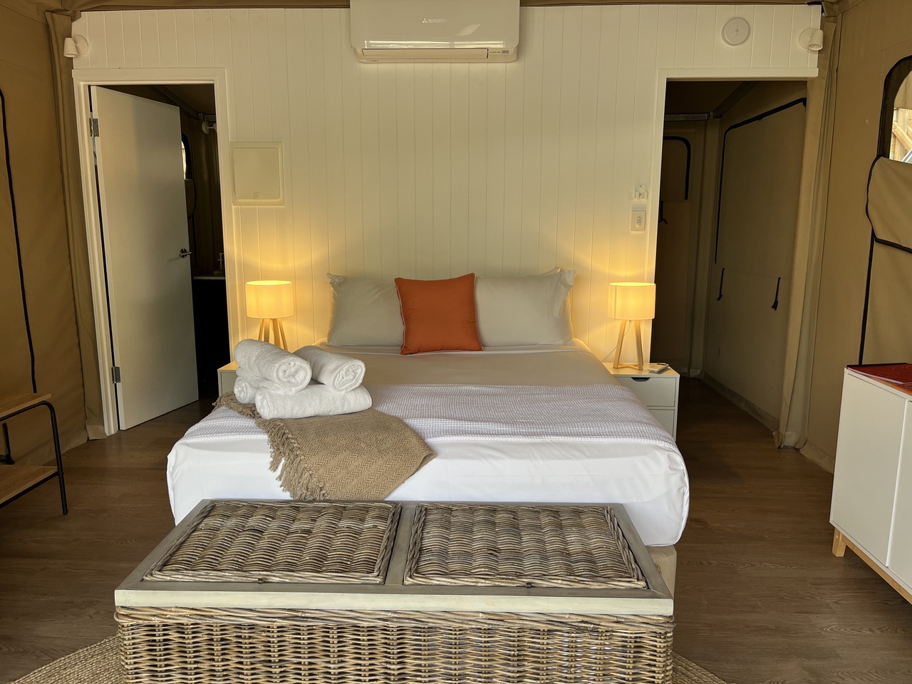 King bed with fresh white linen, warm bedside lamps and air-conditioning inside a Magnetic Glamping safari tent